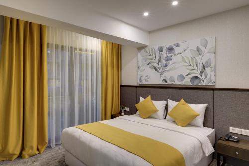 um quarto com uma cama grande e cortinas amarelas em Leo Suites em Bursa