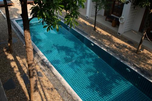 a swimming pool with a blue tile floor and trees at Le Sen Boutique Hotel in Luang Prabang