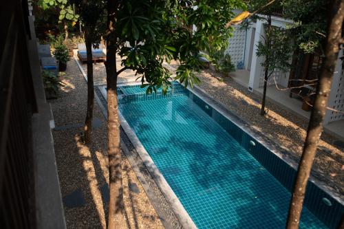a swimming pool with trees in front of a building at Le Sen Boutique Hotel in Luang Prabang