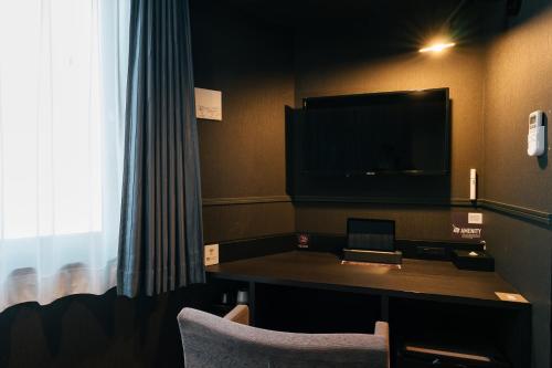 a hotel room with a desk and a tv at mizuka Business Canal City Hakatamae in Fukuoka