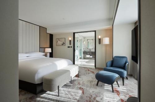 a bedroom with a large bed and a blue chair at Grand InterContinental Seoul Parnas by IHG in Seoul