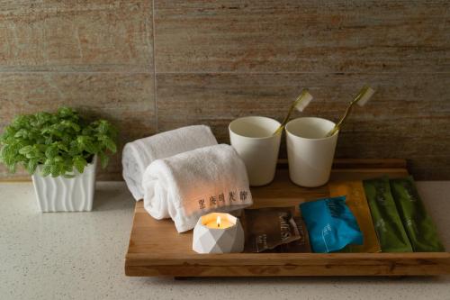 a wooden tray with towels and cups and a candle at Xiang Zhai Jiao C in Jiaoxi