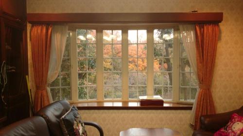 a large window with orange curtains in a living room at Ken House Osaka in Takatuki