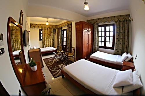 a hotel room with two beds and a desk at Luxor Hotel Hurghada in Hurghada