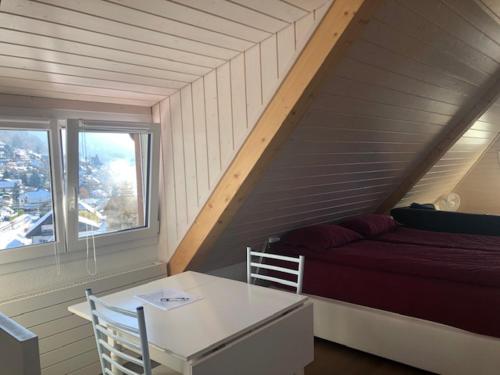 a room with a bed and a table and a table and chairs at La Maison des Copains in Blonay