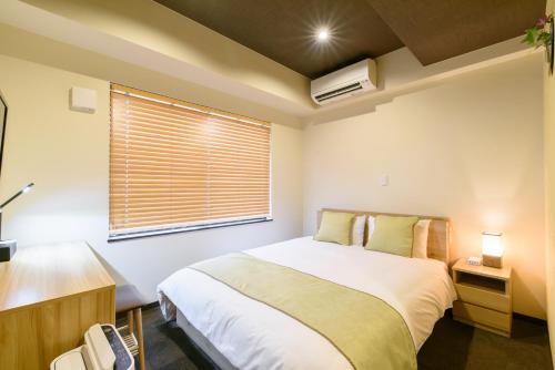 a bedroom with a large white bed and a window at JP INN Kyoto Ekimae Mongakucho in Kyoto