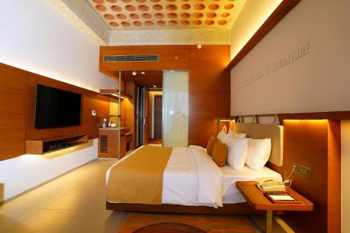 Habitación de hotel con cama y TV en The Centrum en Lucknow
