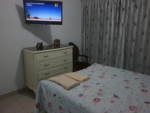 a bedroom with a bed and a dresser with a television at Strenua - Las Quintanas in Trujillo
