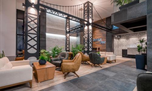 a lobby with couches and chairs and plants at Bridge Hotel in Tbilisi City