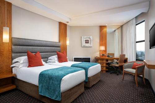 a hotel room with two beds and a desk at Premier Hotel O.R. Tambo in Kempton Park