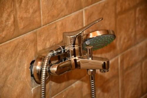 a shower faucet with a shower head on a wall at Om-Abdallah in Aswan