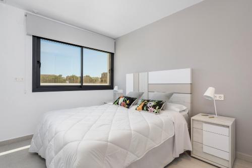 a white bedroom with a large bed and a window at Apartamentos Benimar in Benijófar