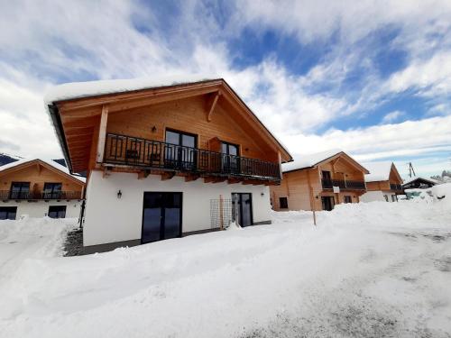 a house with a balcony in the snow at Alpenchalets Nassfeld in Rattendorf