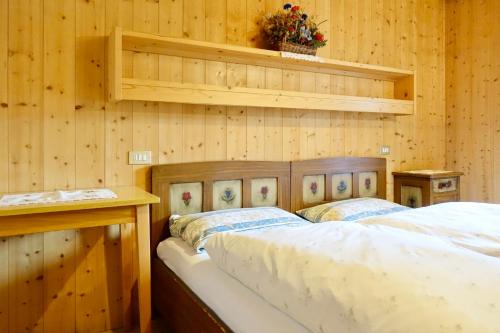 een slaapkamer met 2 bedden in een houten muur bij Ciasa PREROMAN App. vista Castello in San Martino in Badia