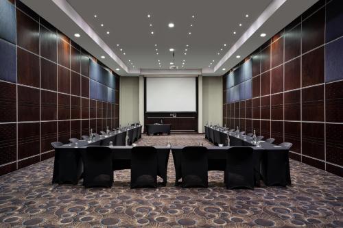 a conference room with rows of tables and a projection screen at Premier Hotel O.R. Tambo in Kempton Park