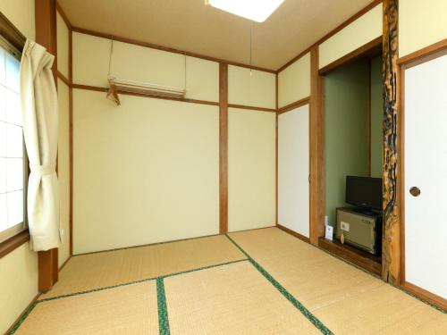 an empty room with a door and a television at Tabataya in Myoko