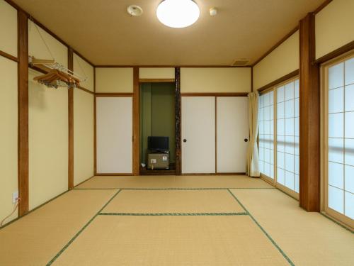 an empty room with a tv and windows at Tabataya in Myoko