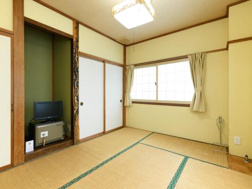 an empty room with a tv and a window at Tabataya in Myoko