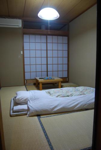 a room with a bed and a table in it at Ougiya Ryokan in Hakuba