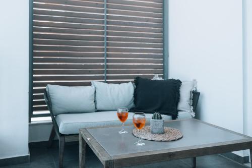 two glasses of wine on a table next to a couch at Seascape Luxury Residences in Agia Pelagia