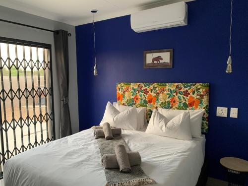 a blue bedroom with a white bed with towels on it at Elephant House, 2 bedroom House, Next to Pilanesberg and Sun City in Mogwase