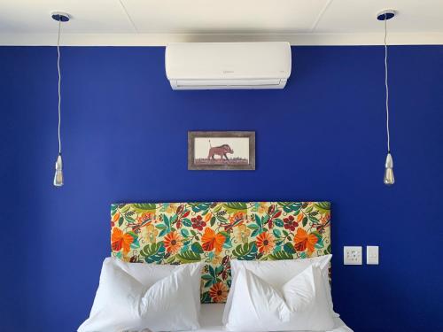 1 dormitorio con pared azul y 1 cama con 2 almohadas en Elephant House, 2 bedroom House, Next to Pilanesberg and Sun City en Mogwase