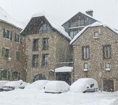 un groupe de voitures recouvertes de neige devant un bâtiment dans l'établissement Hotel Valle De Izas, à Sallent de Gállego