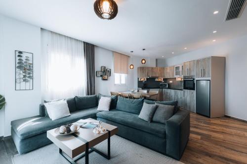 a living room with a blue couch and a kitchen at Seascape Luxury Residences in Agia Pelagia