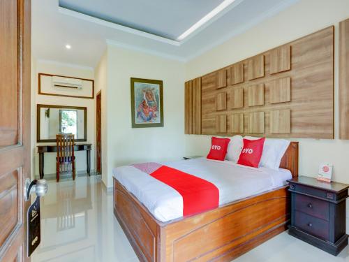 a bedroom with a bed with red pillows and a table at OYO 1762 Hotel Astiti Graha Tanah Lot in Tanah Lot