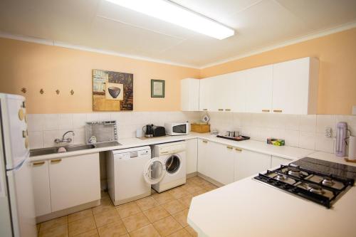 a kitchen with white cabinets and a washer and dryer at Sneezewood in Dullstroom