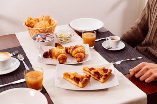 un tavolo con piatti di prodotti da forno e tazze di caffè di Hotel Sole a Prato Nevoso