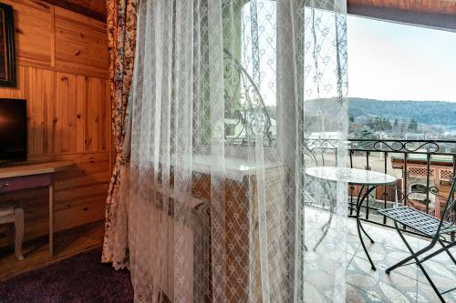 a room with a window with a table and a balcony at Emerald House in Mykulychyn