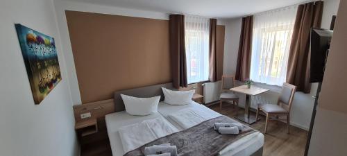 1 dormitorio con 1 cama, mesa y sillas en Pension am Stern, en Leipzig