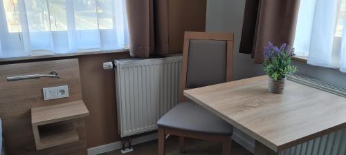 a wooden table with a chair and a vase of flowers on it at Pension am Stern in Leipzig