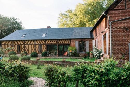 een groot bakstenen huis met een patio in de tuin bij Le Pré Doré in Bonneville-la-Louvet