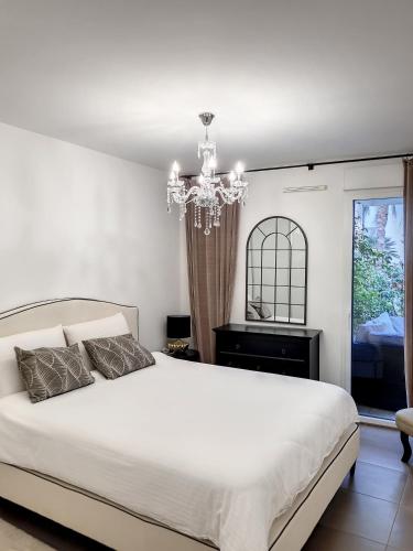 - une chambre avec un lit blanc et un lustre dans l'établissement Apartment Palm Beach with a nice swimming pool, à Cannes