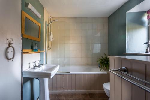 y baño con bañera, lavabo y aseo. en Parnham Cottage, en Bridport