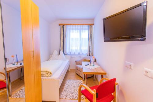 a small room with a bed and a tv at Landhaus Tritscher in Schladming