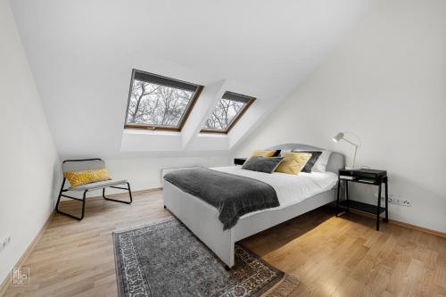 a white bedroom with a bed and two windows at Kaunas Old Town apartment with underground parking in Kaunas
