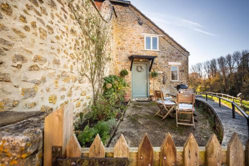 a stone house with a green door and a wooden fence at Parnham Cottage in Bridport