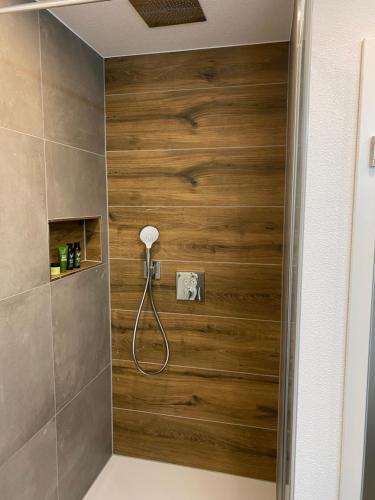 a shower in a bathroom with a wooden wall at Haus Schiltach in Schramberg