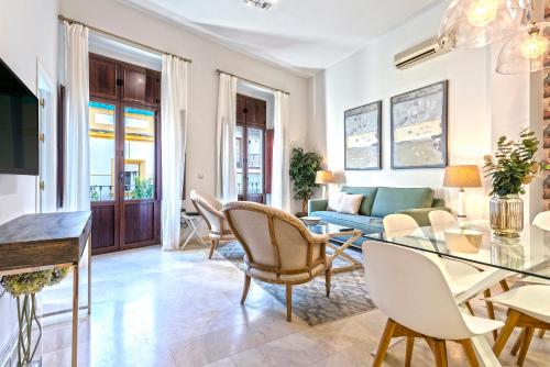 Una sala de estar con una mesa de cristal y sillas. en Genteel Home Arfe Terrace, en Sevilla