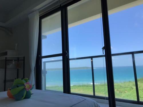 a bedroom with large windows and a bed with a stuffed animal at 嵵裡仙人掌海景民宿Ocean view room in Magong