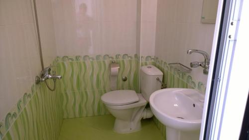 a green and white bathroom with a toilet and a sink at House of Flowers in Ahtopol