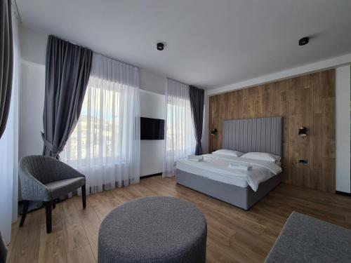 a bedroom with a bed and a chair and windows at Motel BTG in Tomislavgrad