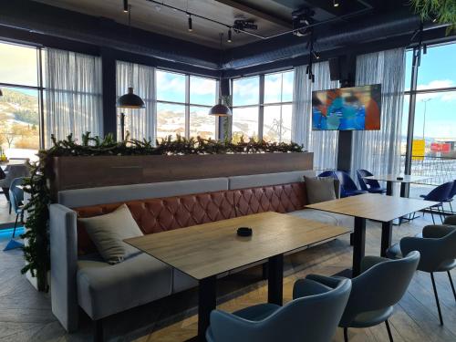 a restaurant with two tables and a couch and windows at Motel BTG in Tomislavgrad