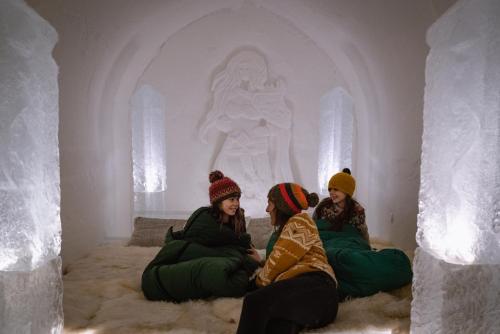 three girls sitting on a bed in an ice cave at Sorrisniva Igloo Hotel in Alta