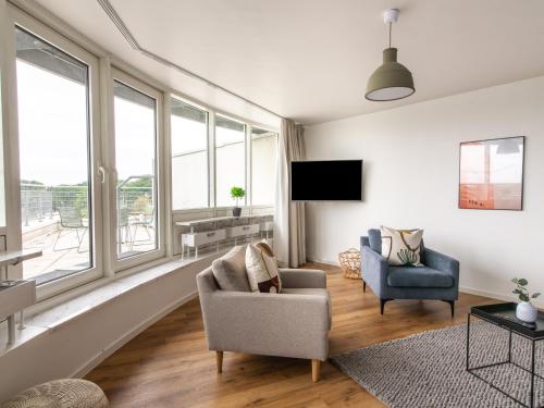 a living room with two chairs and a tv at Limehome Wolfsburg Porschestraße in Wolfsburg