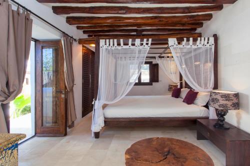 a bedroom with a bed with mosquito netting at Can Ribas Ibiza in Sant Llorenç de Balafia