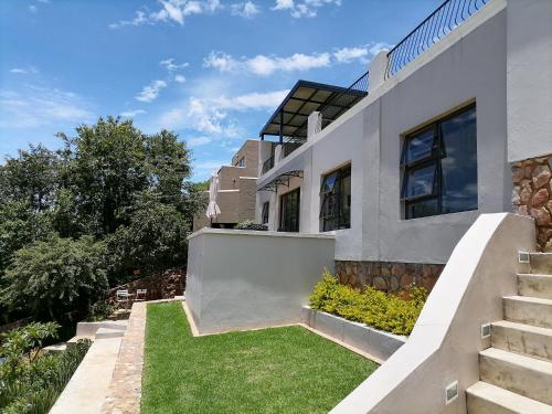 une maison blanche avec des escaliers et de la pelouse dans l'établissement CityView, a stunning modern apartment, à Johannesbourg